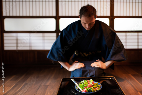 Traditional japanese house or ryokan restaurant with black lacquered table and salad dish with man in kimono or yukata background of shoji doors