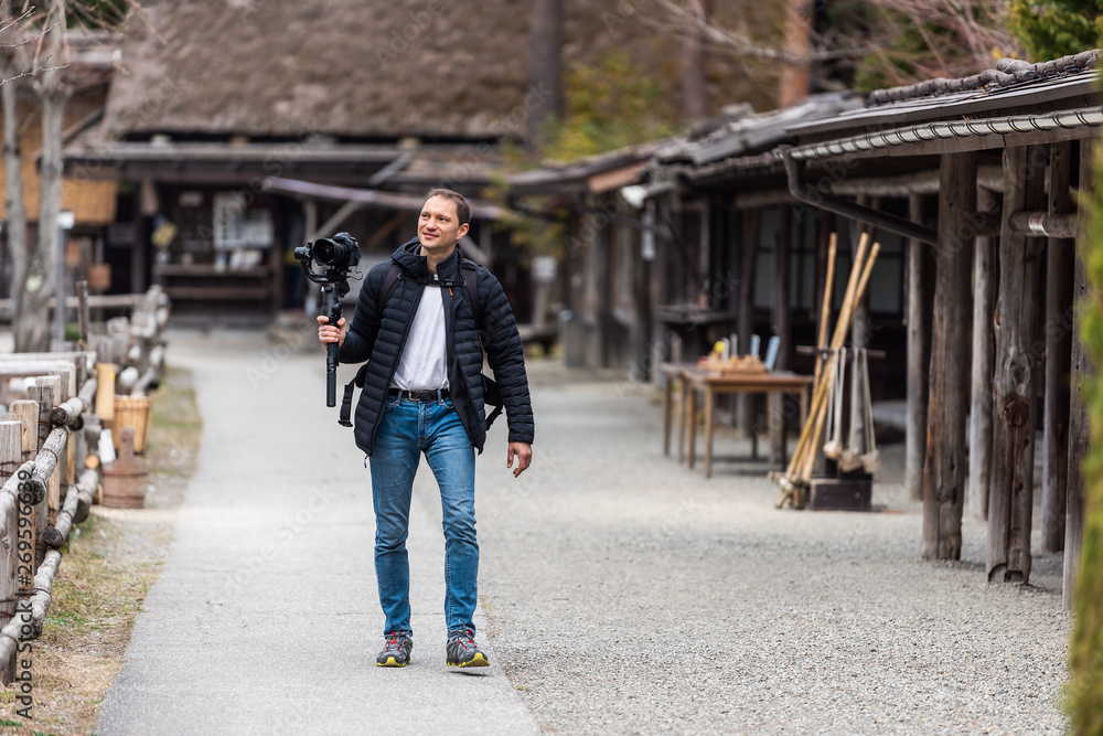 Takayama, Japan Wooden houses buildings in traditional Hida no Sato old folk village with trail path and young tourist man walking in Gifu prefecture