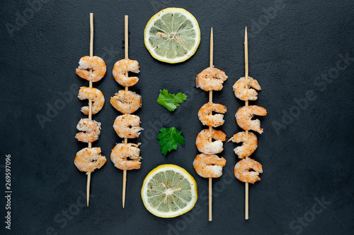 Grilled shrimp shashlik. shrimps with parsley and lemon on the background of concrete