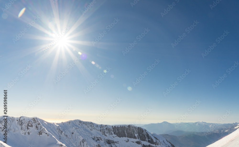 Bright sun over the Caucasus mountains covered by snow in the ski resort of Sochi, Russia.