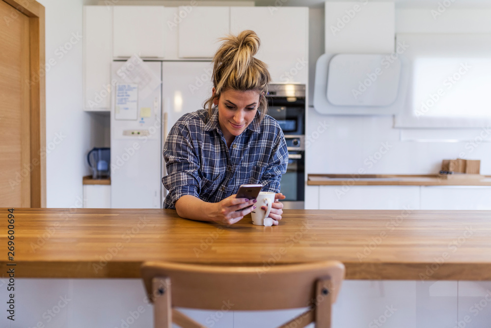 beautiful and young woman having breakfast at home and having fun and chatting with the smartphone beautiful and young woman having breakfast at home and having fun and chatting with the smartphone