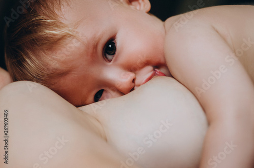 A Mother breastfeeding her little baby in her arms. close up mom nursing and feeding small kid. selective focus, noise effect