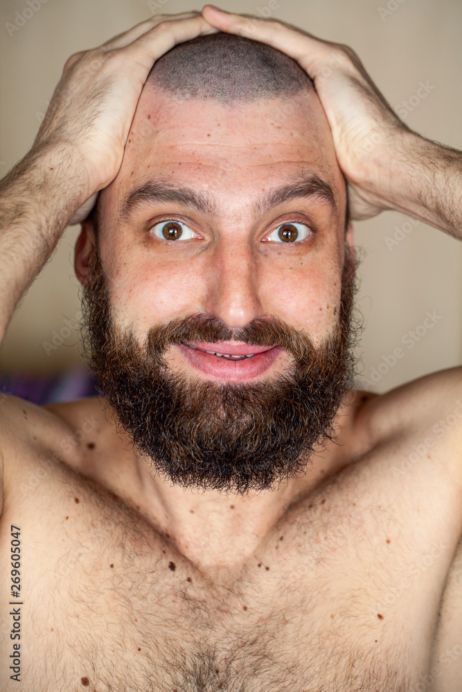 Obraz premium Portrait of man with an unusual hairstyle and beard with a naked torso, looks into the camera 