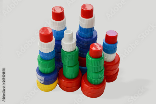 Tower of colorful plastic bottle caps simulating a city with skyscrapers isolated on white background