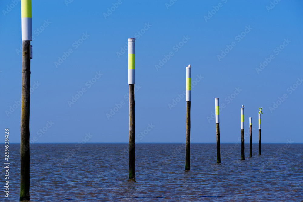 Wooden poles in the north sea against clear blue sky