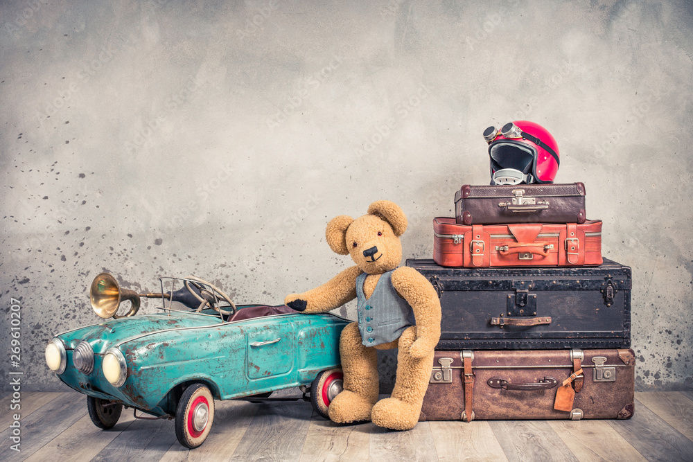 Teddy Bear toy standing near rusty retro pedal car from 60s, antique