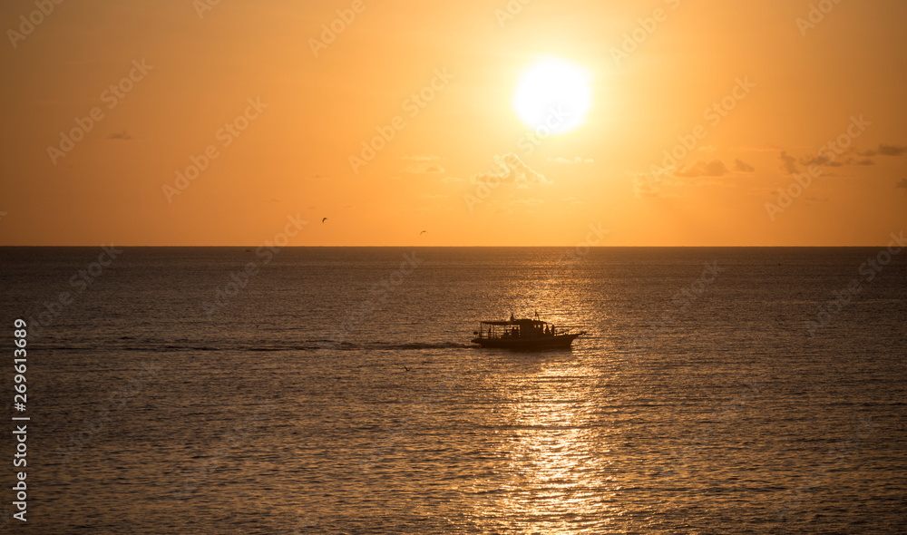 Boat sailing at Sunset in the Atlantic Ocean. Fernando de Noronha, northeastern Brazil.
