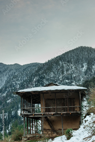 Snow covered wooden house in mountains - Majestic winter landscape in himalayas
