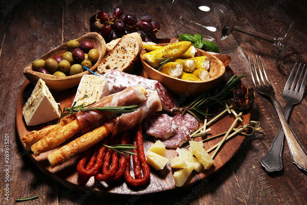 antipasto various appetizer. Cutting board with prosciutto, salami, cheese, bread and olives on dark wooden background antipasto various appetizer. Cutting board with prosciutto, salami, cheese, bread and olives on dark wooden background
