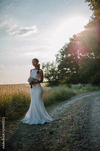 Beautiful bride gives poses in the field with her bouquet © Halit