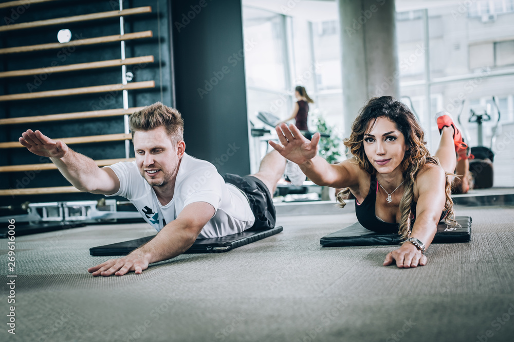 Attractive fitness woman with coach doing hard exercise in gym Attractive fitness woman with coach doing hard exercise in gym