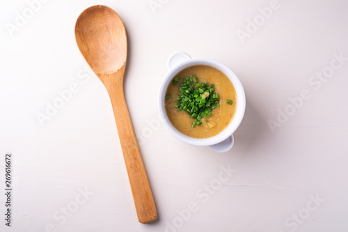 Soup puree with onion in the white plate top view with wooden spatula