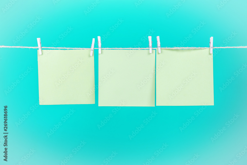 Green stickers on clothesline with clothespins isolated on blue background. Place for your text. Green stickers on clothesline with clothespins isolated on blue background. Place for your text.