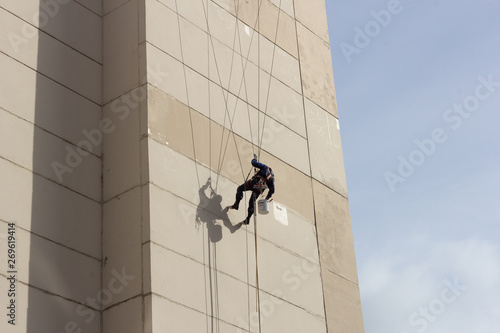 climber repairs a wall suspended on four cables