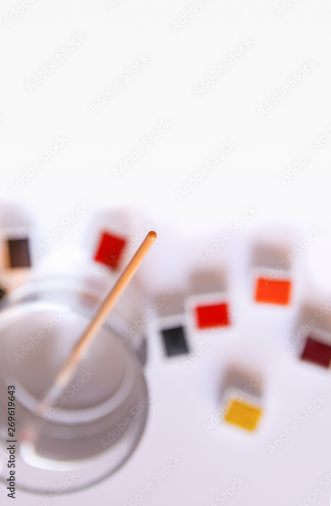 Watercolor paints, brush, water in glass and paper on white background. Flat lay, top view Watercolor paints, brush, water in glass and paper on white background. Flat lay, top view