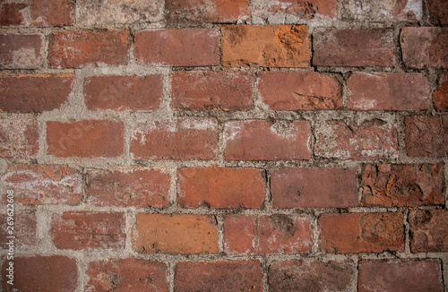 Antique red brick wall with damaged bricks.