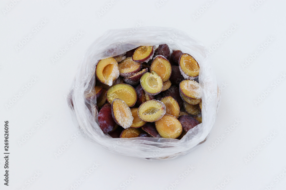 Frozen plums in a transparent package located on a white background