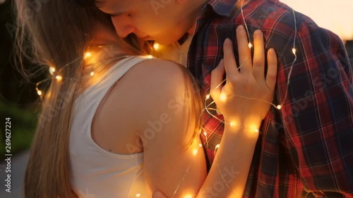 Care and love expression. Sincere and intimate embrace. Closeup of young couple wrapped in fairy lights photo