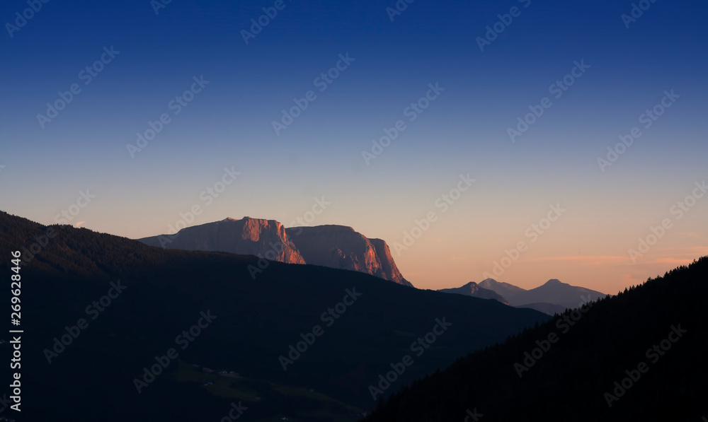 Dolomites mountains at sunset with empty and clean blue sky