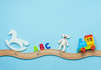 Kids toys on toy wooden railway on blue background with blank space for text