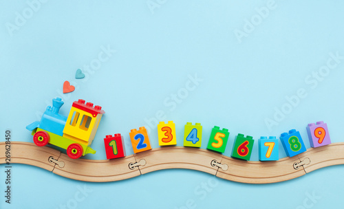 Kids toy train with numbers on toy wooden railway on light blue background with copy space