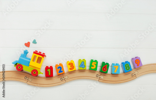 Kids toy train with numbers on railway on white wooden background with copy s...