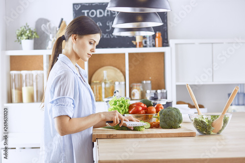 A young woman prepares food in the kitchen. Healthy food - vege