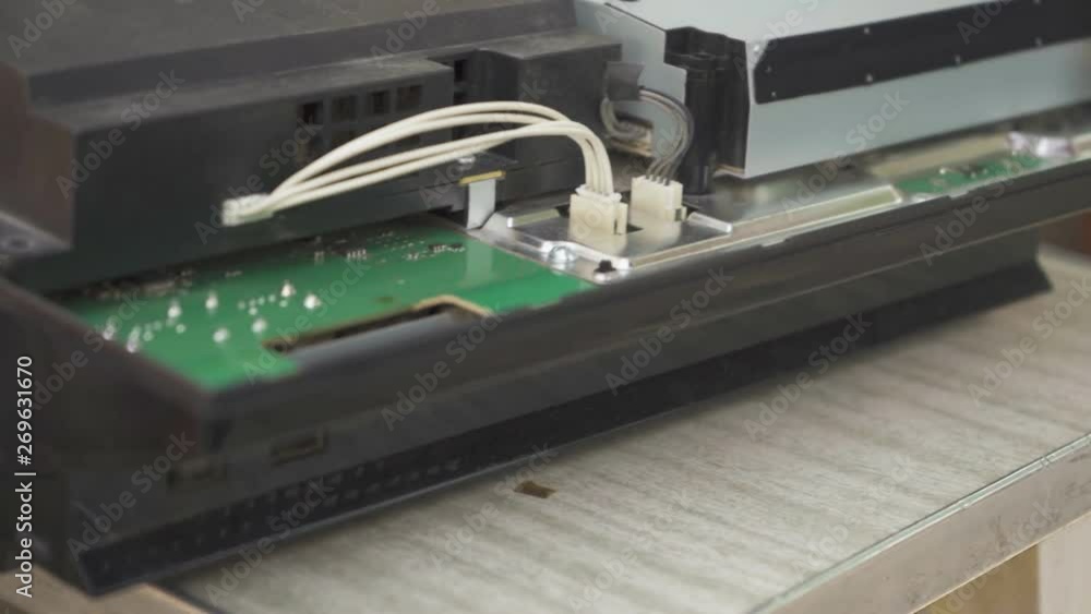 A man cleans the game console board from dust with a brush A man cleans the game console board from dust with a brush