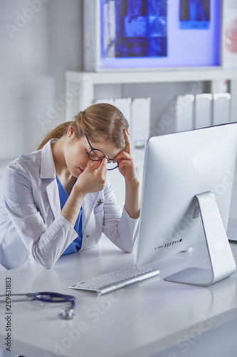 Young female doctor tired after working with computer