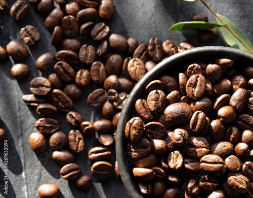 black bowl with coffee beans scatered on the table dark background top view window light photo