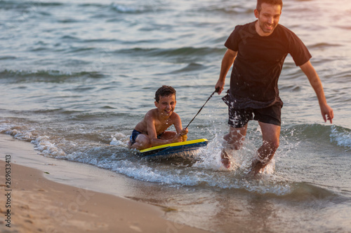 Father and son surfing on boogie boards on the sunset photo