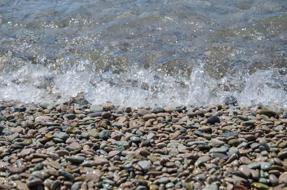 Background of seashore, pebble beach and transparent sea close up Background of seashore, pebble beach and transparent sea close up