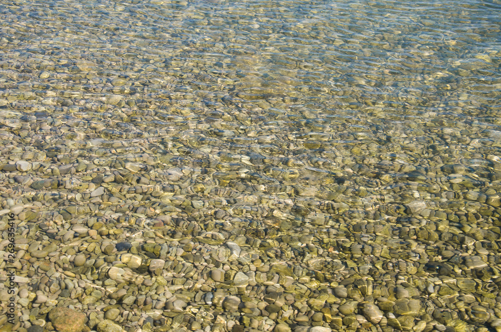 Abstract sea background, view on ripple surface of water, stone bottom underwater Abstract sea background, view on ripple surface of water, stone bottom underwater