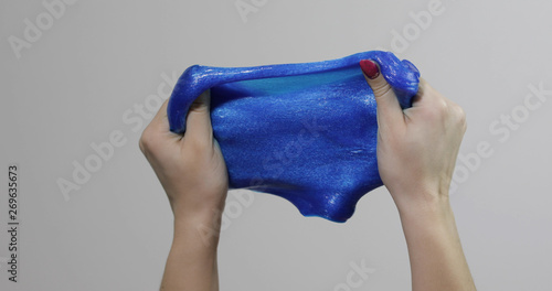 Fotografi Woman hands playing with oddly satisfying blue slime gooey substance