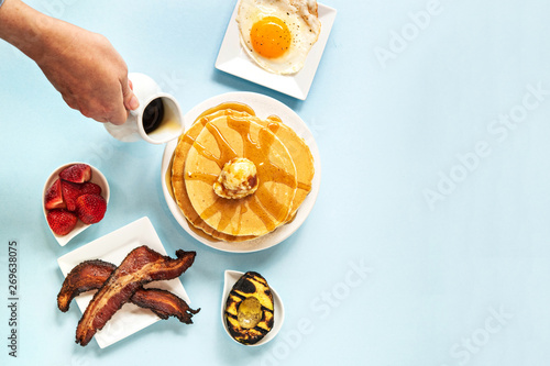 Hand pouring syrup on pancakes 