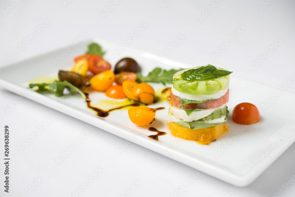 Caprese salad on a white square plate Caprese salad on a white square plate