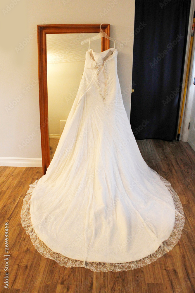 Obraz premium A beautiful wedding dress hangs on a mirror