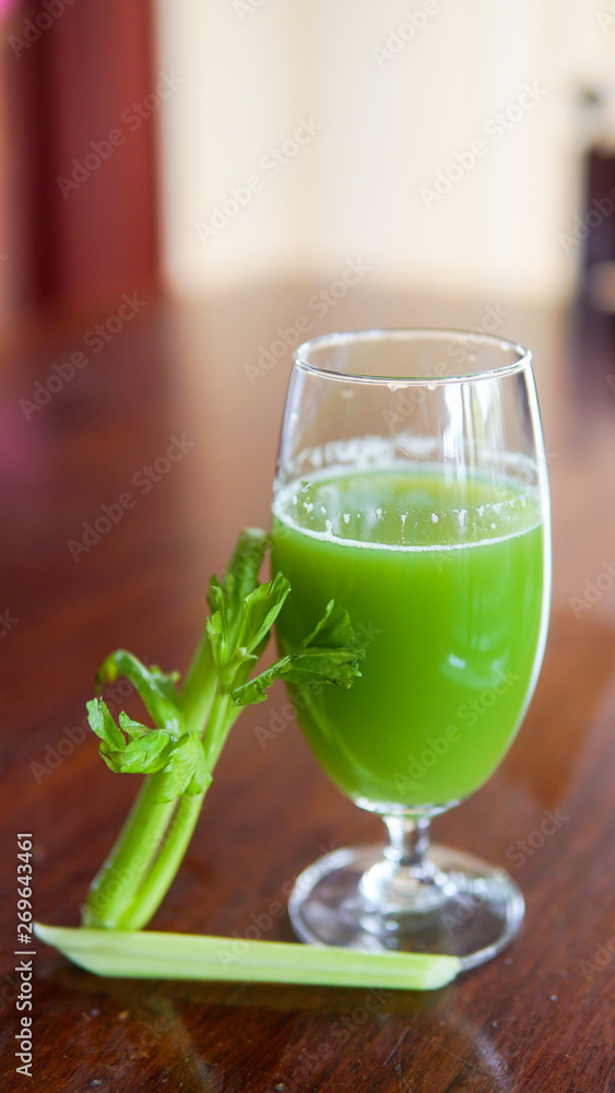 Fresh green celery juice in glass on wooden brown background Fresh green celery juice in glass on wooden brown background