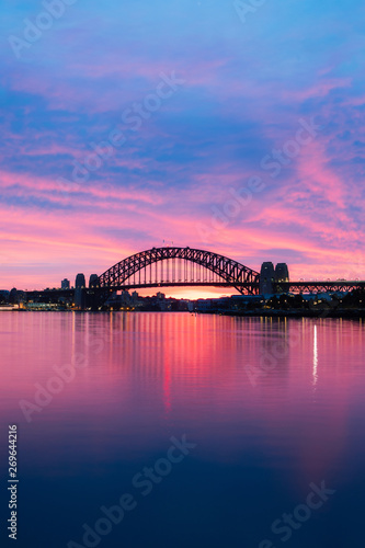 Silhouette of Sydney Harbour Bridge at dawn with blue and purple sky.