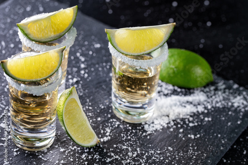 Tequila with lime and salt on a black background