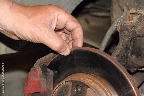 Check of the thickness of the brake disc, car mauntenance - close up hand points your fingers at the unvented brake disk