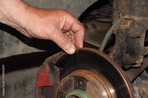 Test of thickness of the brake disk, car diadnostics - man hand points your fingers at the unventilated brake disc