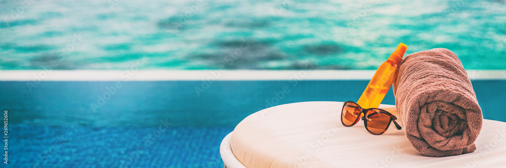 Luxury vacation banner background of sunscreen, sunglasses for sun protection on towel and lounger at hotel infinity swimming pool for sun tan summer relaxation panoramic banner. - obrazy, fototapety, plakaty 