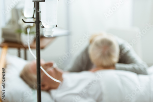 selective focus of sad senior woman with husband in coma in clinic photo