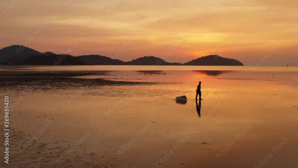 Silhouette of a fisherman at sunset, fishing while lower level water in the sea Silhouette of a fisherman at sunset, fishing while lower level water in the sea