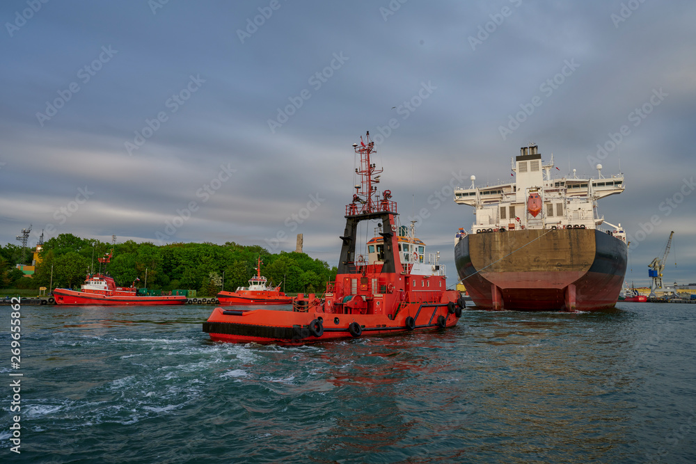 The Port of Gdansk, Poland, tugs enter the port of a large merchant ship The Port of Gdansk, Poland, tugs enter the port of a large merchant ship