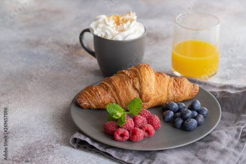 Continental breakfast, French croissant, coffee with milk, fruit and orange juice. Good morning concept.