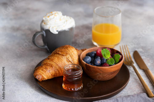 Continental breakfast, French croissant, coffee with milk, fresh berries and orange juice. Good morning concept.
