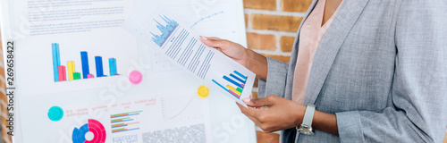 panoramic shot of african american Casual businesswoman near flipchart holding paper in loft office