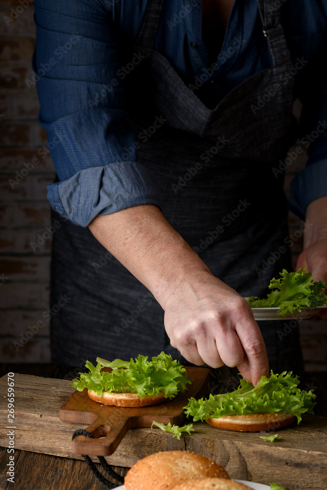 Home cooking burgers and french fries with your hands on a dark wooden background. -